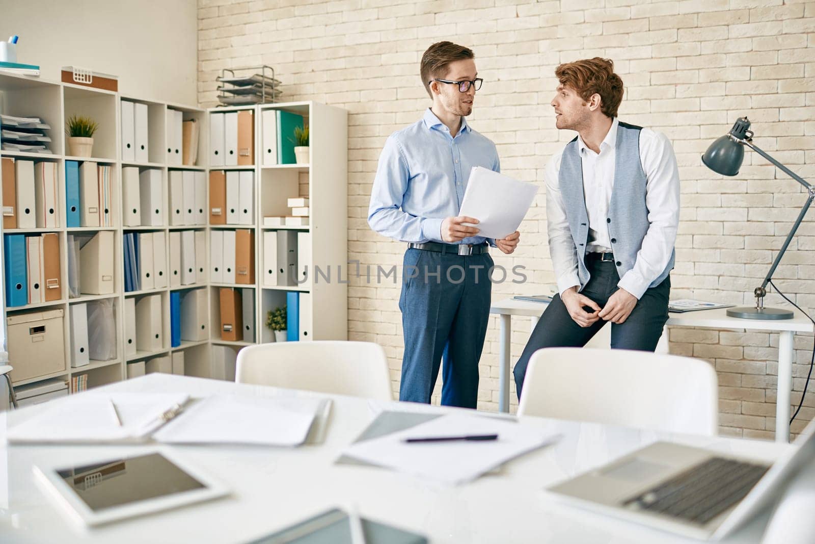 Two male employees discussing plans in office