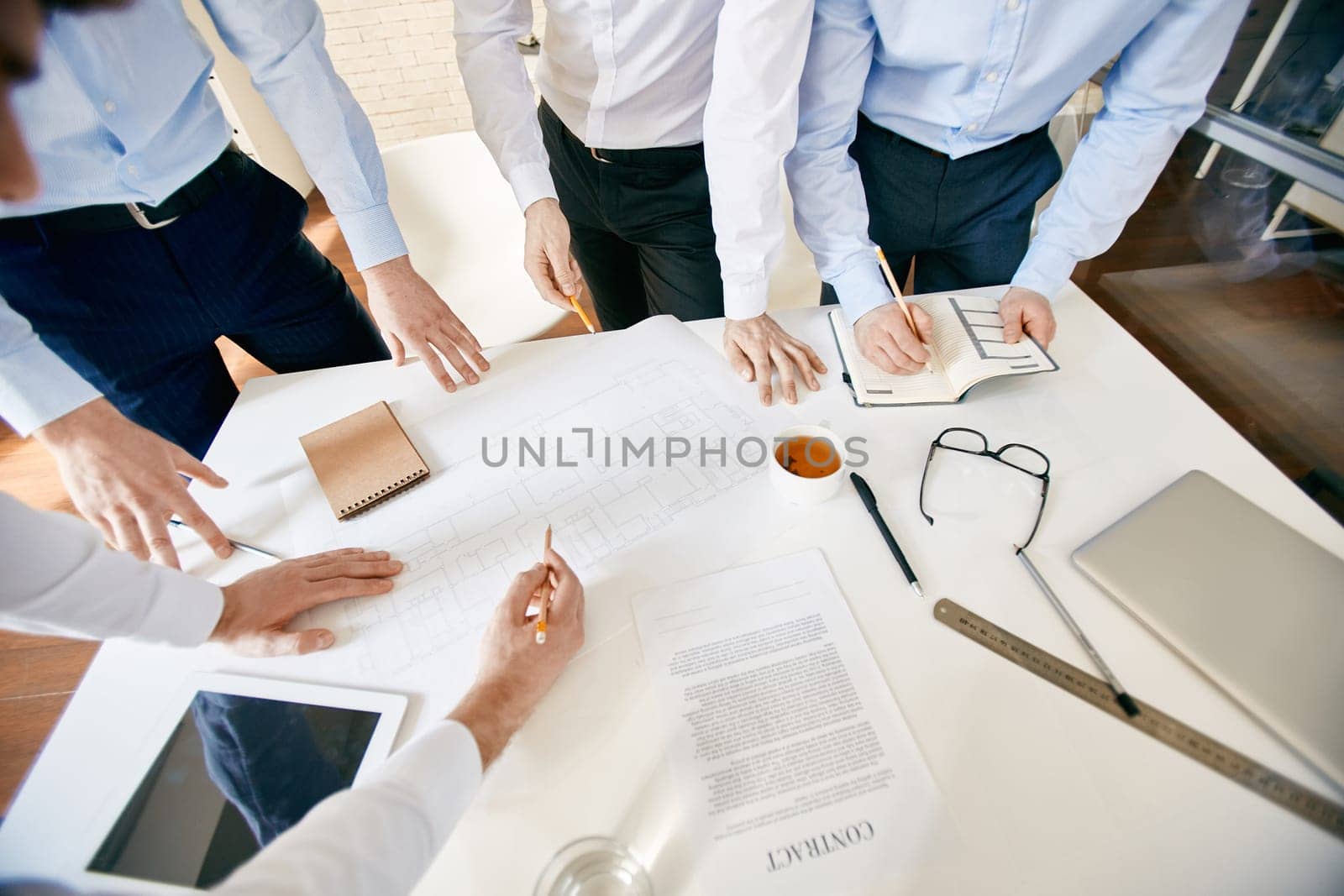 Group of architects with pencils discussing sketch at workplace