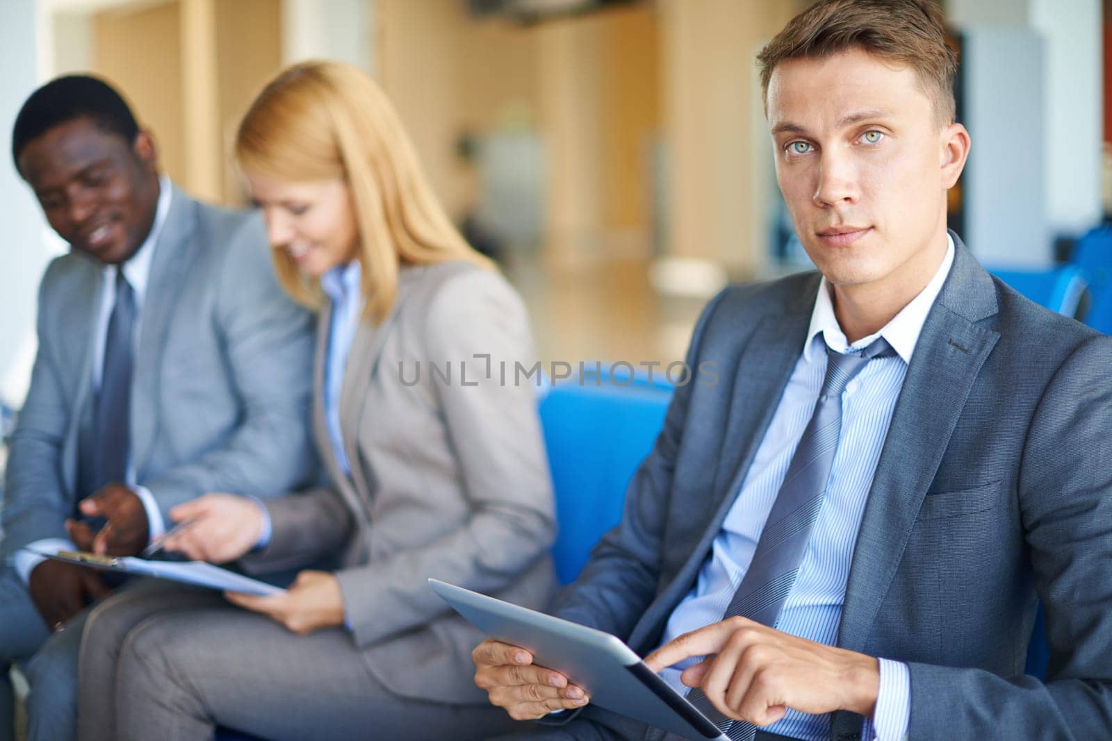Young businessman with touchpad looking at camera