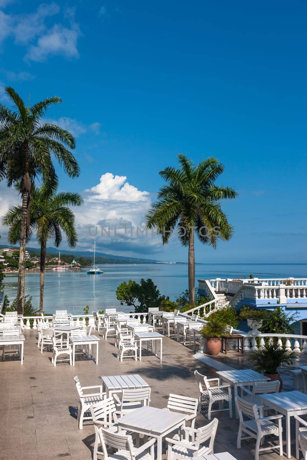 White tables and chairs  in tropical garden  on a beautiful  beach of Jamaica