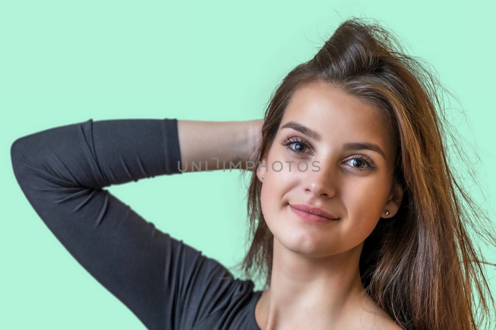 Portrait of smiling long haired beautiful girl on the green background. Horizontally.