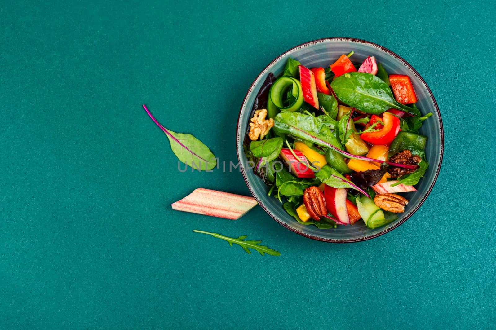 Vitamin delicious salad of rhubarb, bell pepper, herbs and nuts in bowl. Space for text