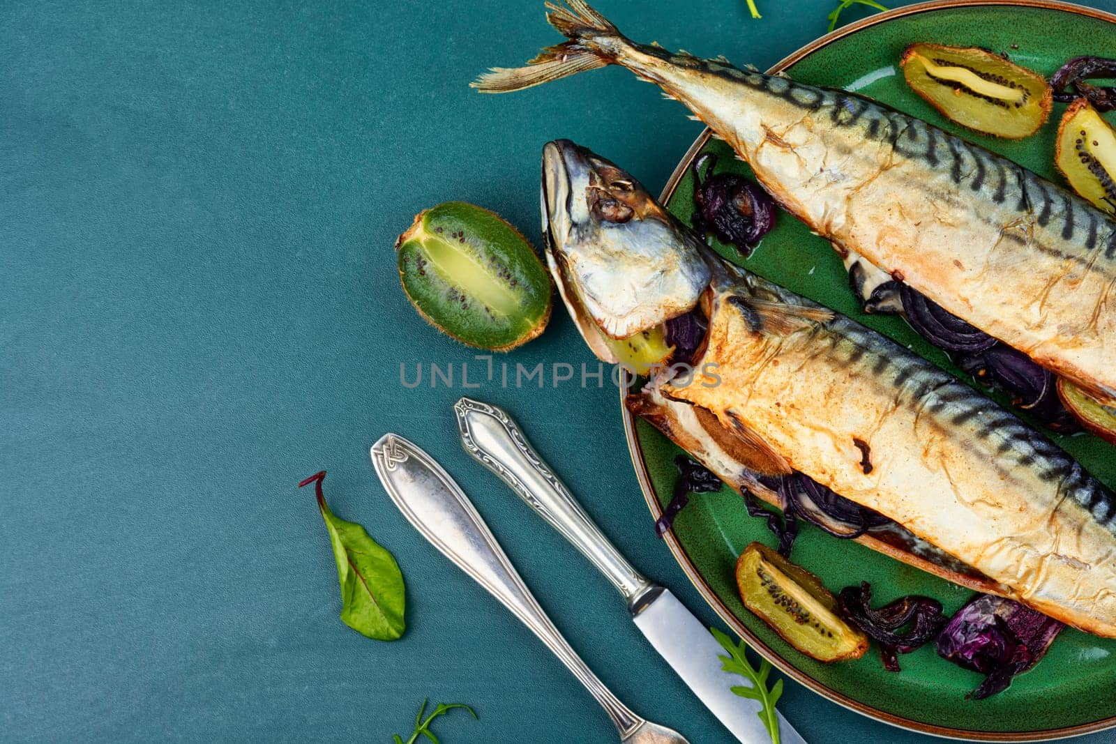 Two appetizing mackerel fish baked with kiwi pieces. Top view