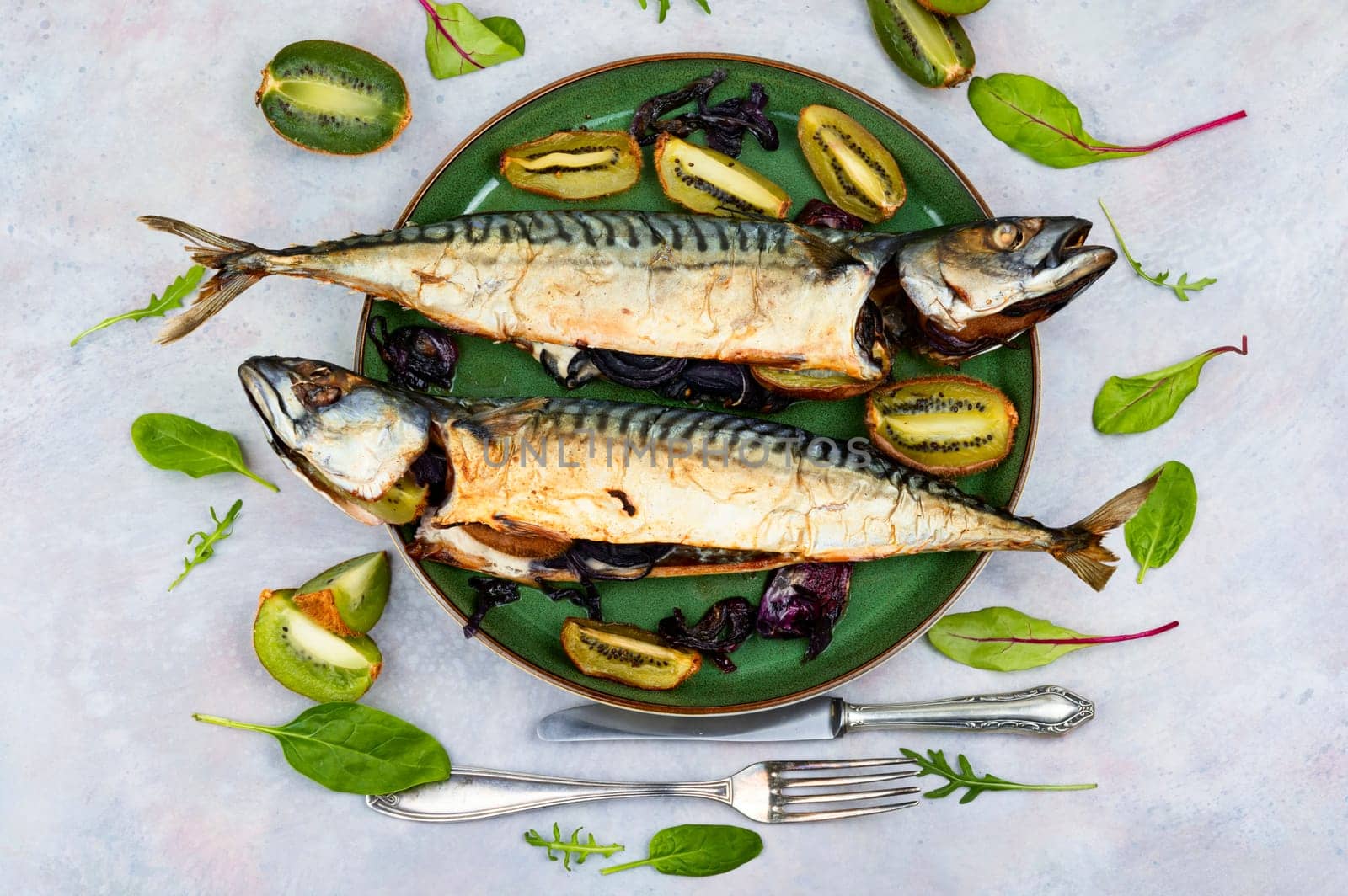 Two appetizing mackerel fish baked with kiwi pieces. Top view