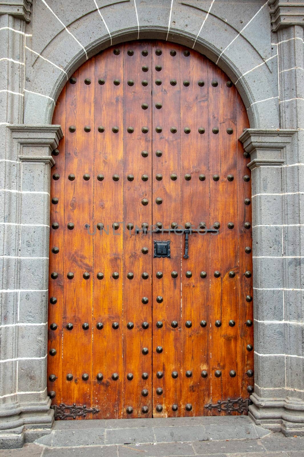 Old massive large wooden door in a stone wall of a church.
