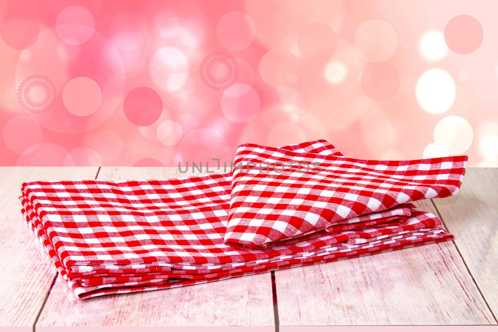 Empty wooden bright desk table with red checkered tablecloth over abstract blurred bright background. Template for your food and product display montage.