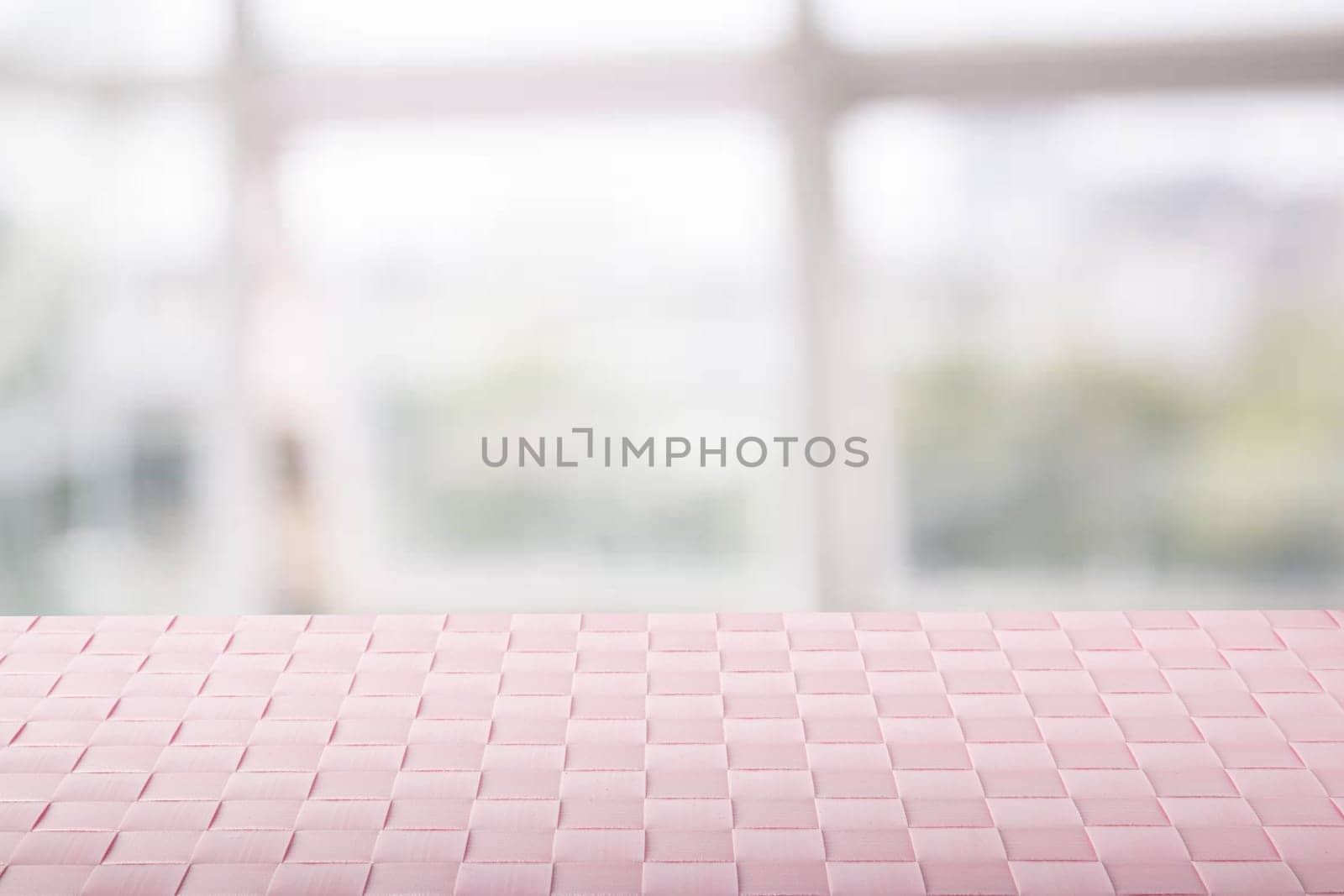 Empty table product. Closeup of a empty pink tablecloth or napkin on table over abstract blurred bright windows background. Template for your food and product display montage.