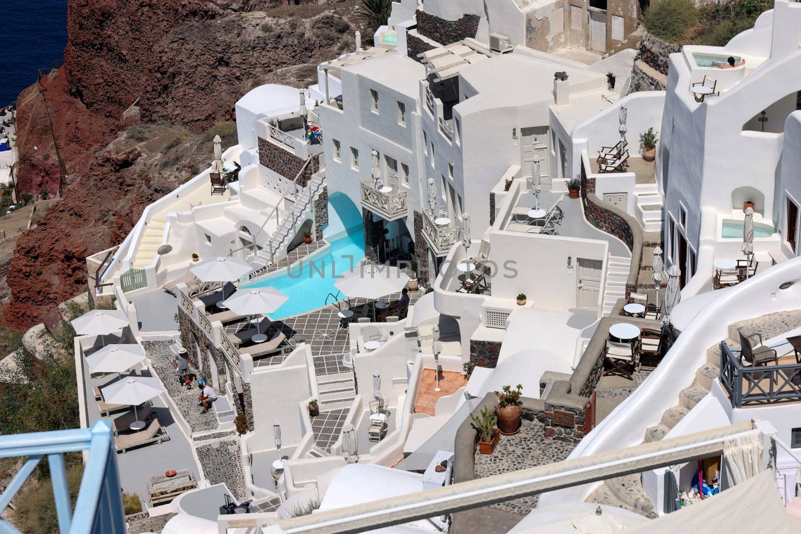 Oia, Santorini, Greece - July 3, 2021: Whitewashed houses with terraces and pools and a beautiful view in Oia on Santorini island, Greece