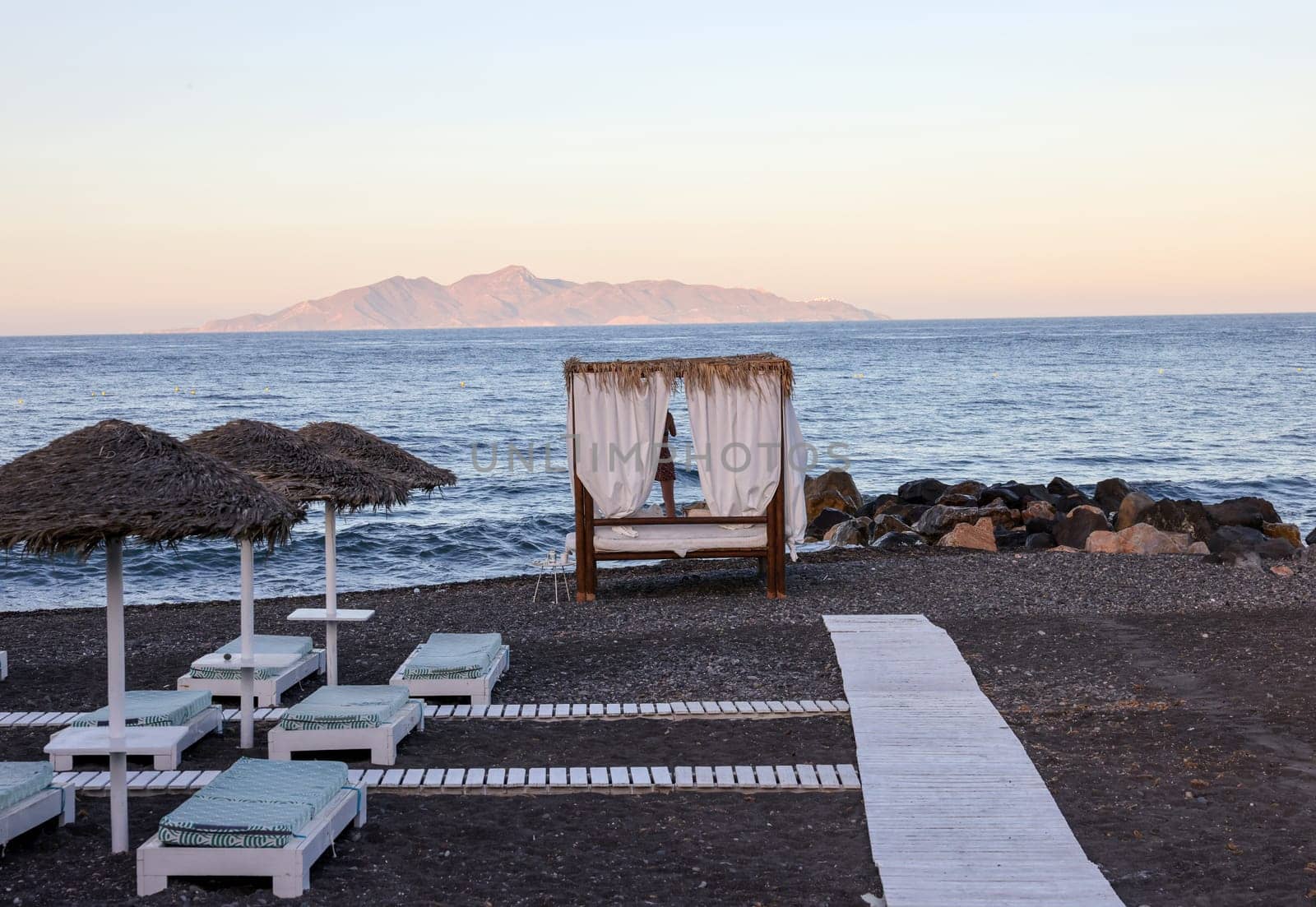 Sun loungers on the black volcanic beach of Kamari in Santorini. Cyclades, Greece