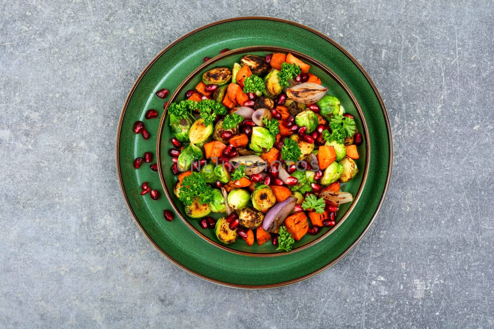 Salad with Brussels sprouts, carrots, with parsley and pomegranate seeds. Healthy vegetarian food