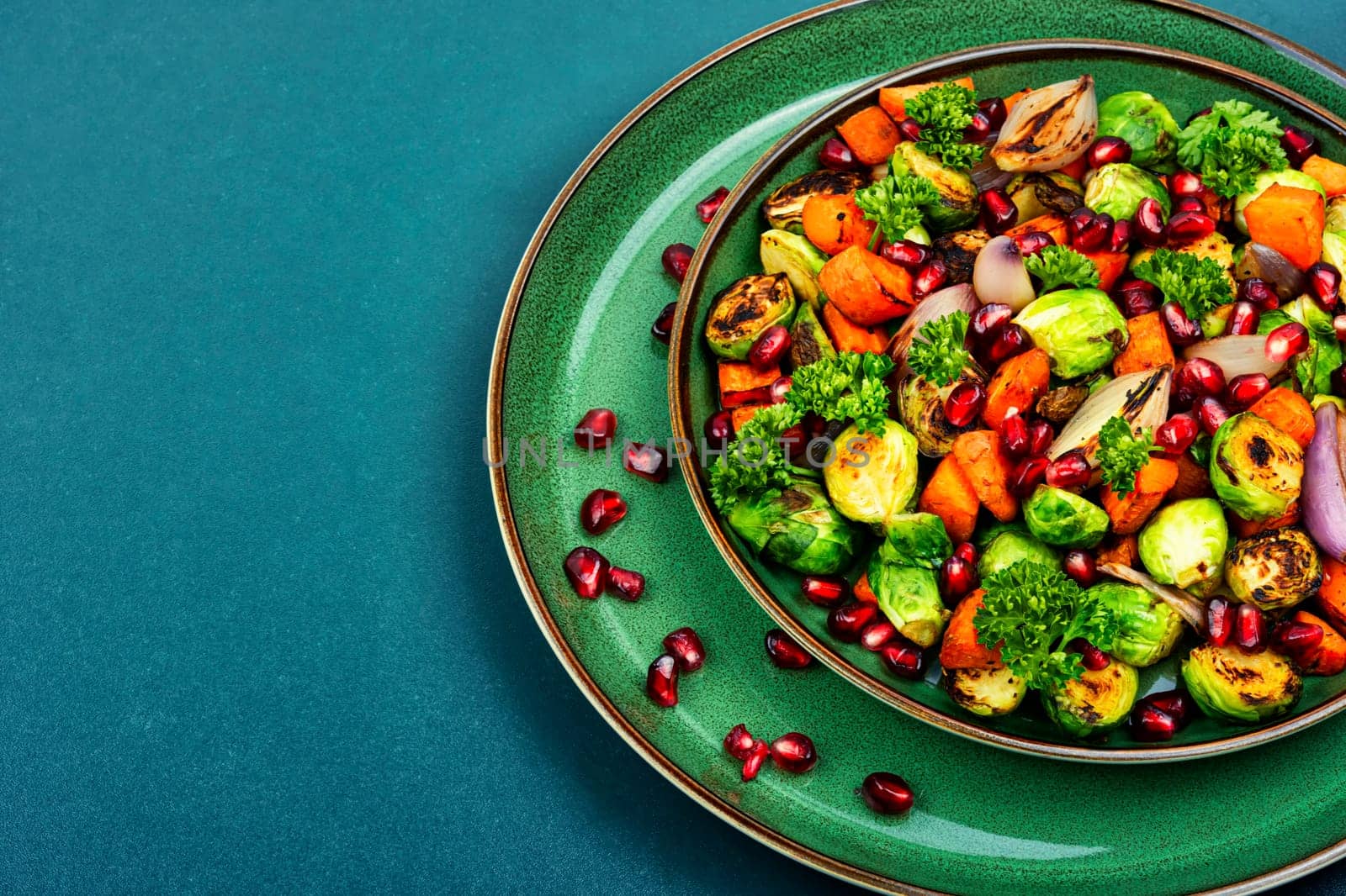 Salad with Brussels sprouts, carrots, with parsley and pomegranate seeds. Healthy vegetarian food