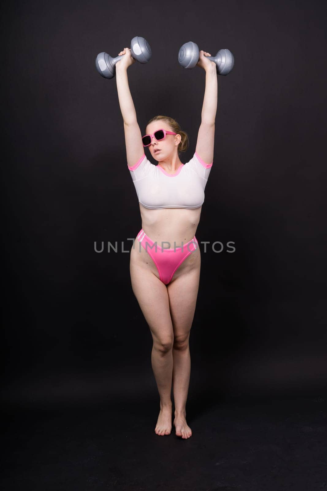 Strong sportswoman in boxing gloves prepared high kick. Isolated on a white, red, yellow background