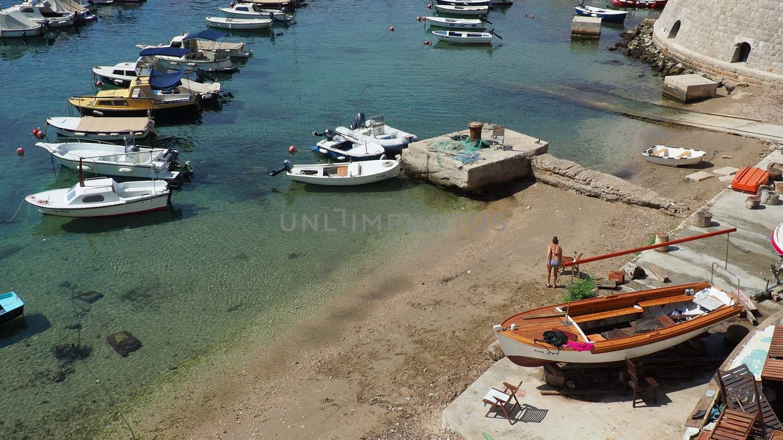 Dubrovnik, Croatia, August 14, 2022. City port in summer, tourist attraction. Tourists walk, get into boats and ships and go on boat trips. Adriatic Sea. A local resident plays with a dog. Old forts