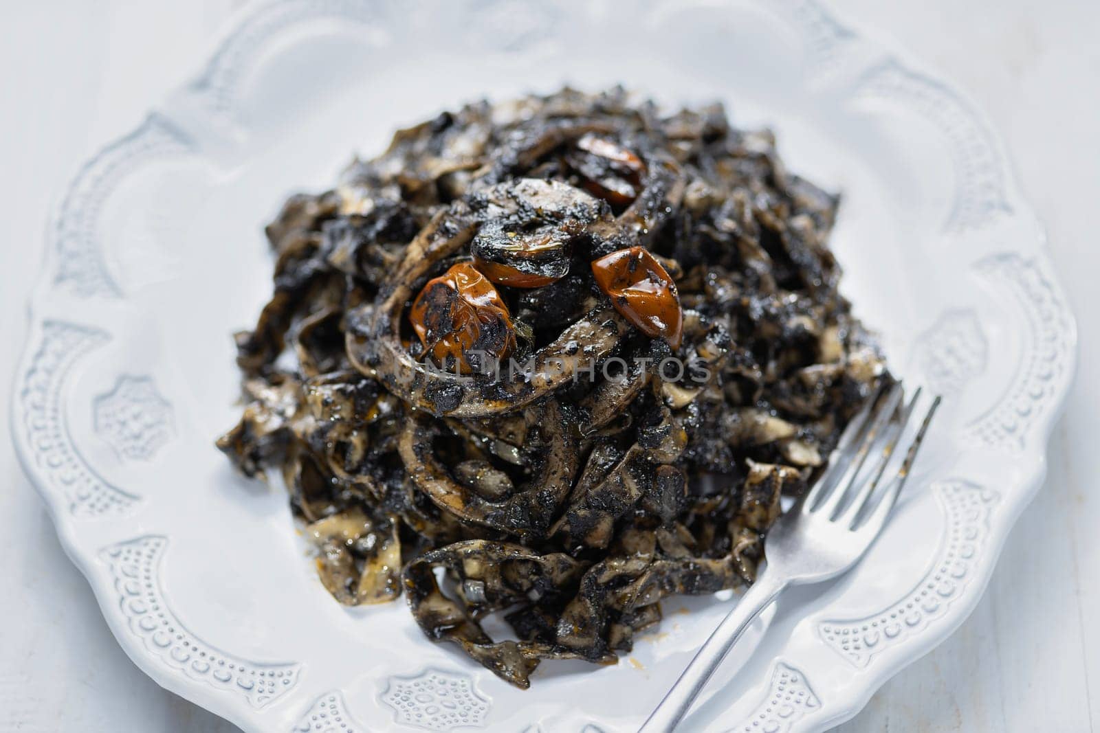 close up of plate of squid ink tagliatelle pasta