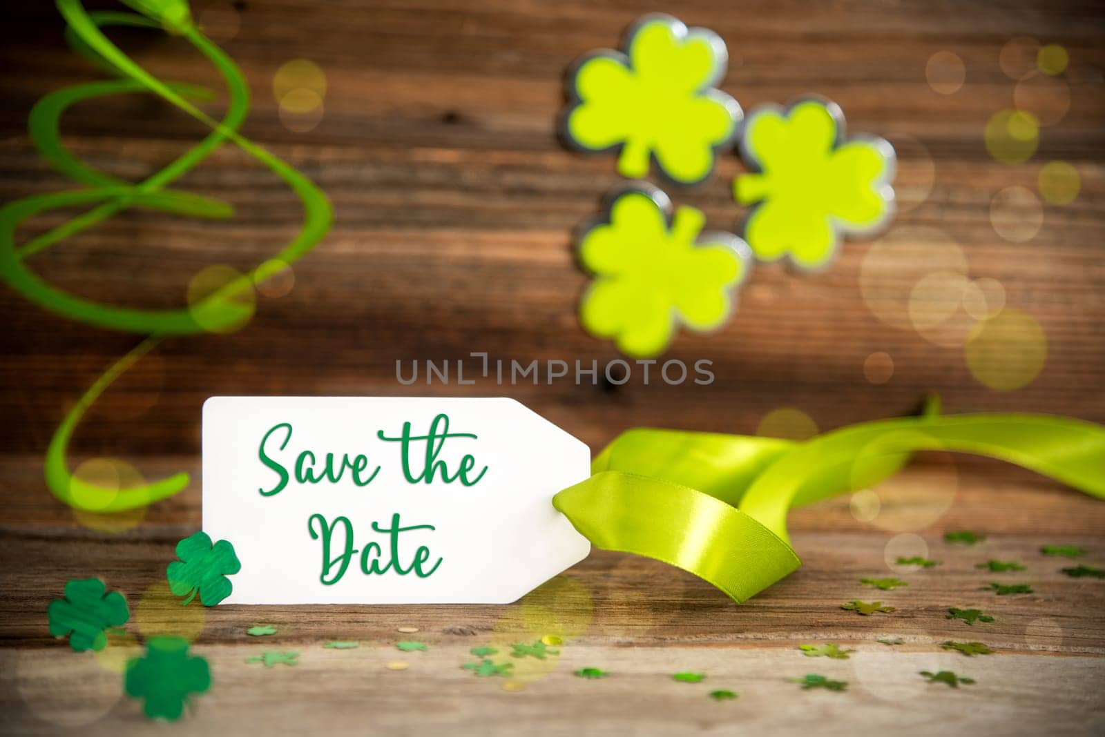 White Label With English Text Save The Date. Saint Patrick's Day Decoration With Green Clover And Shamrock. Wooden Vintage Background With Festive Ribbon.