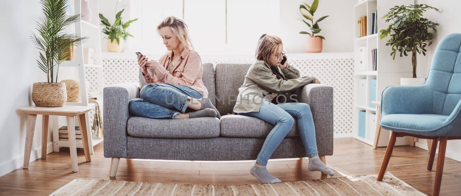 Quarreled mother and daughter sitting on the sofa back to back. Concept of the family relation.