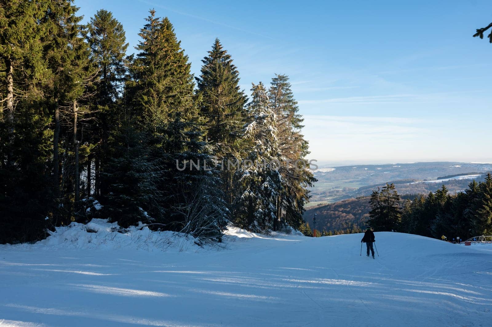 Ski slope on the Wasserkuppe with skiers, with blue sky and trees