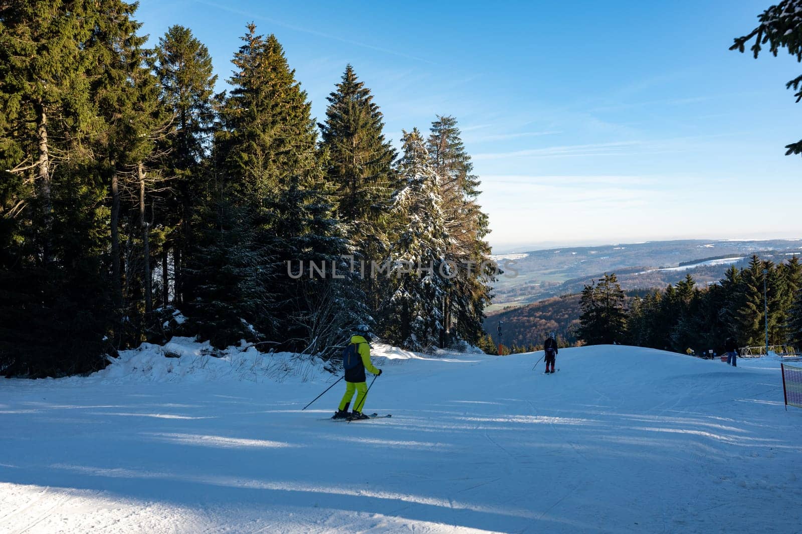 Ski slope on the Wasserkuppe with skiers, with blue sky and trees