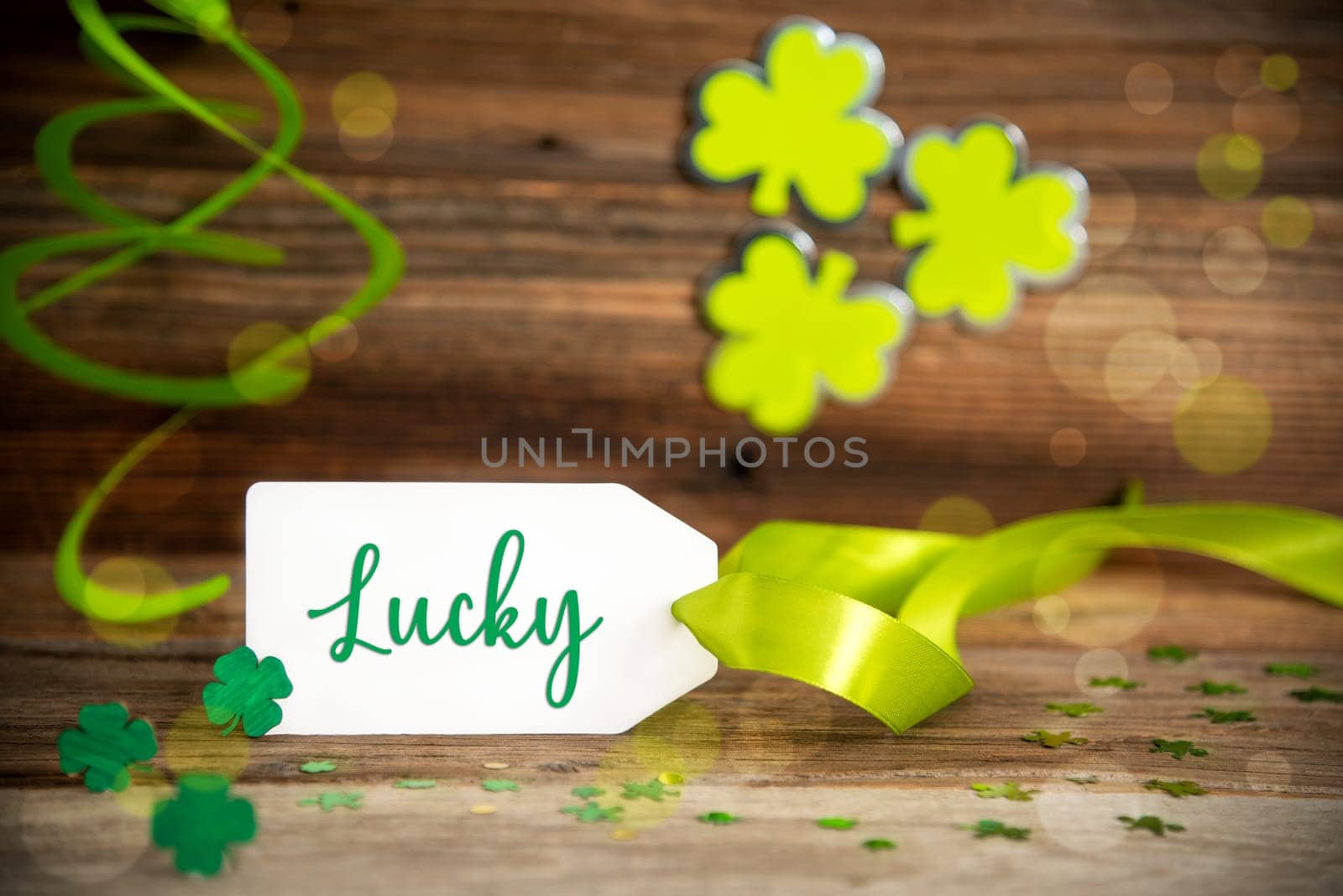 White Label With English Text Lucky. Saint Patrick's Day Decoration With Green Shamrock And Clover. Wooden Vintage Background With Festive Ribbon.