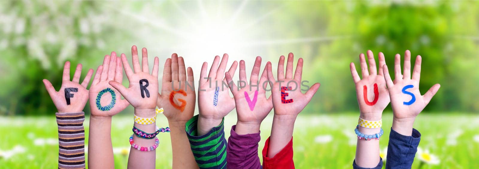 Children Hands Building Colorful English Word Forgive Us. Sunny Green Grass Meadow As Background
