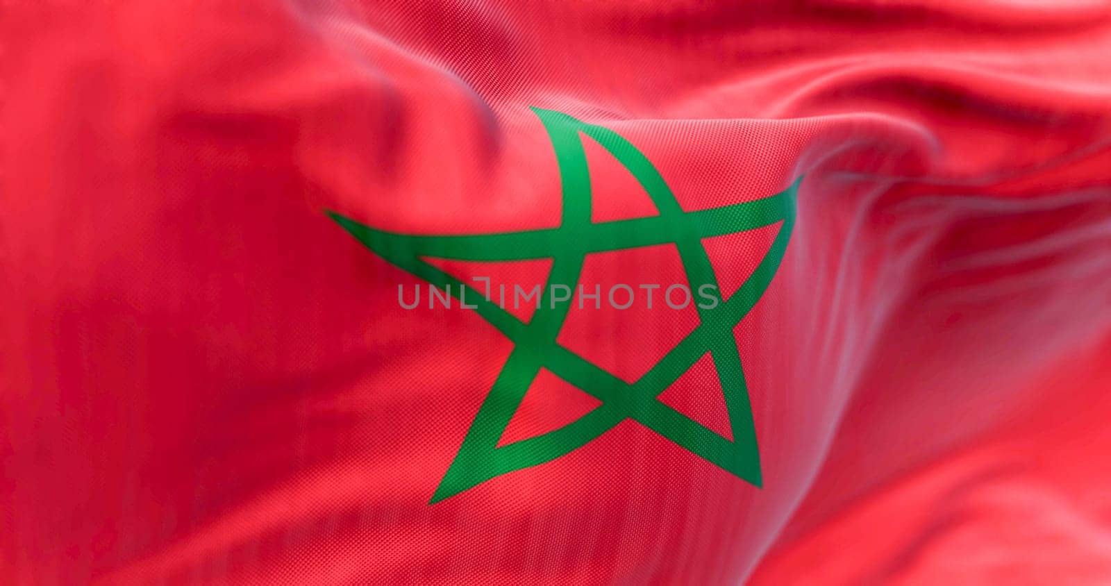 Detail of the Morocco national flag waving in the wind. Red flag with a green pentagram in the center. 3d illustration render. Selective focus. Close-up. Textured background