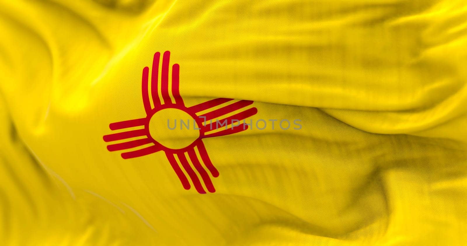 Detail of the New Mexico state flag waving. Red sun, symbol of the Zia people, displayed on a yellow background. 3d illustration render. Selective focus. Close-up. Textured background