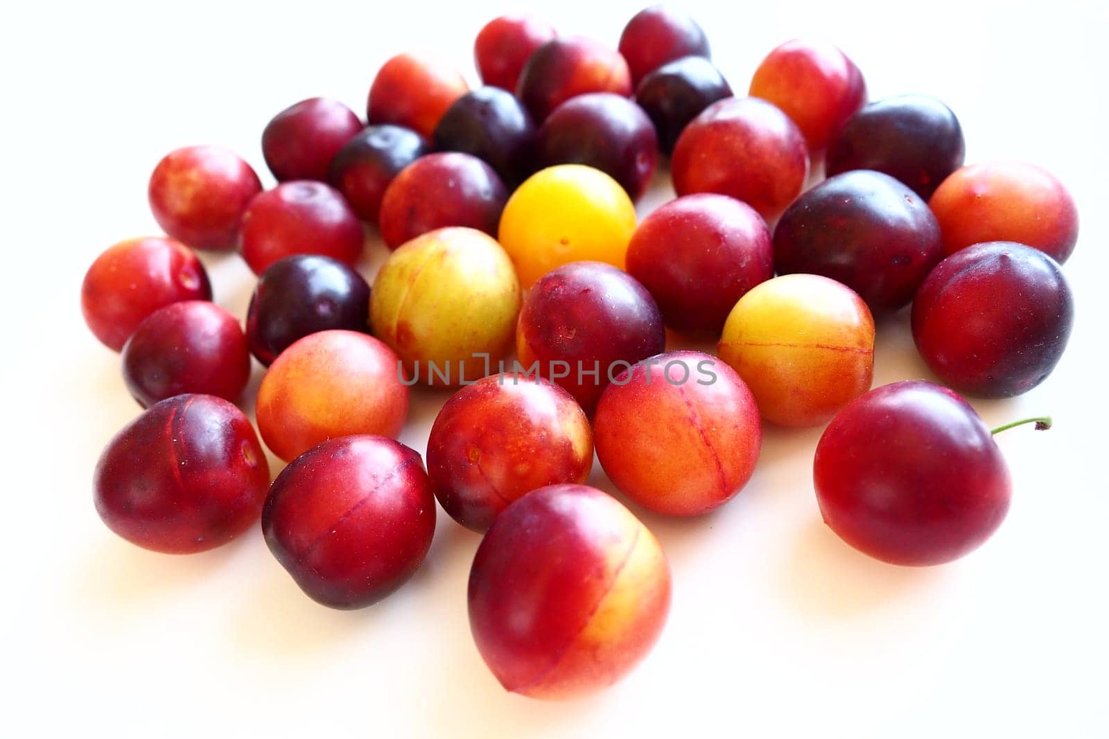 Cherry plum on a white background. A yellow-red cherry plum mix just removed from a tree. Delicious fresh plum berries. Appetizing large cherry plum for sale catalog. Food on a white background.