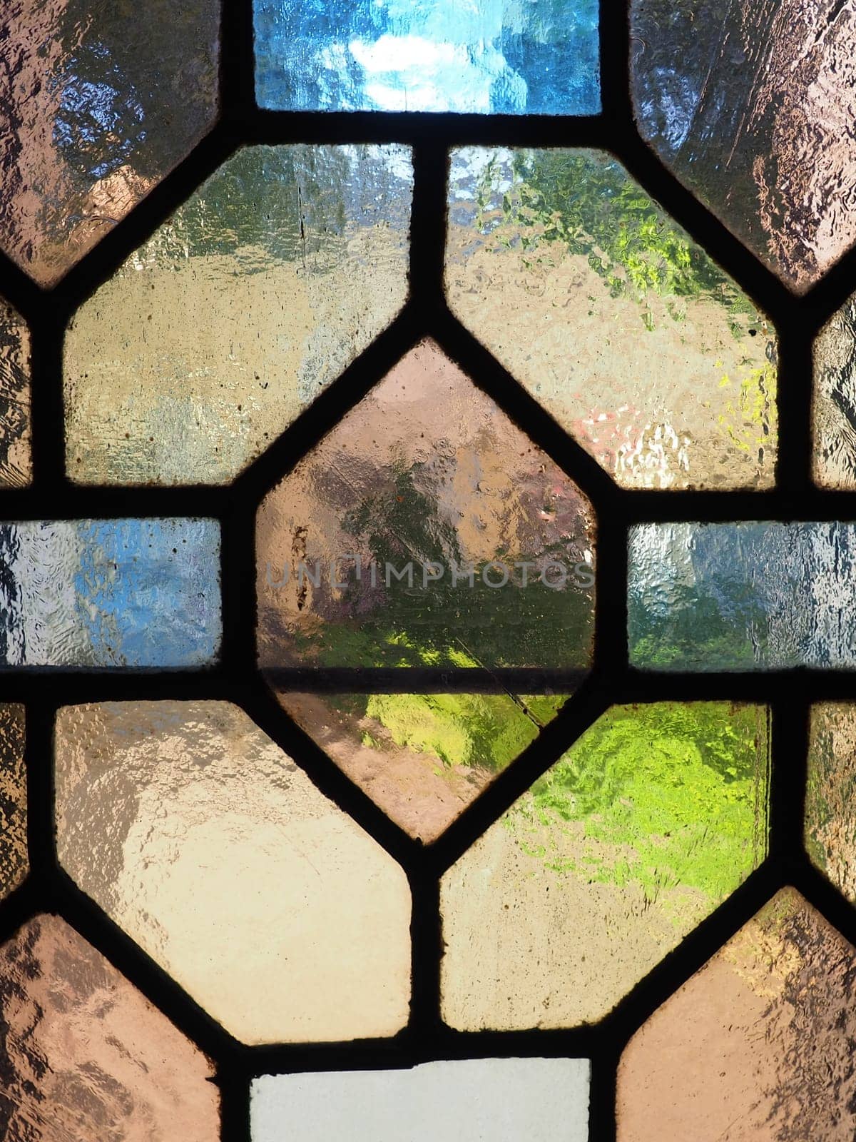 Window with vintage stained glass. Multi-colored pieces of transparent glass. A beautiful window through which light enters the room. Decoration of an old Christian church or temple