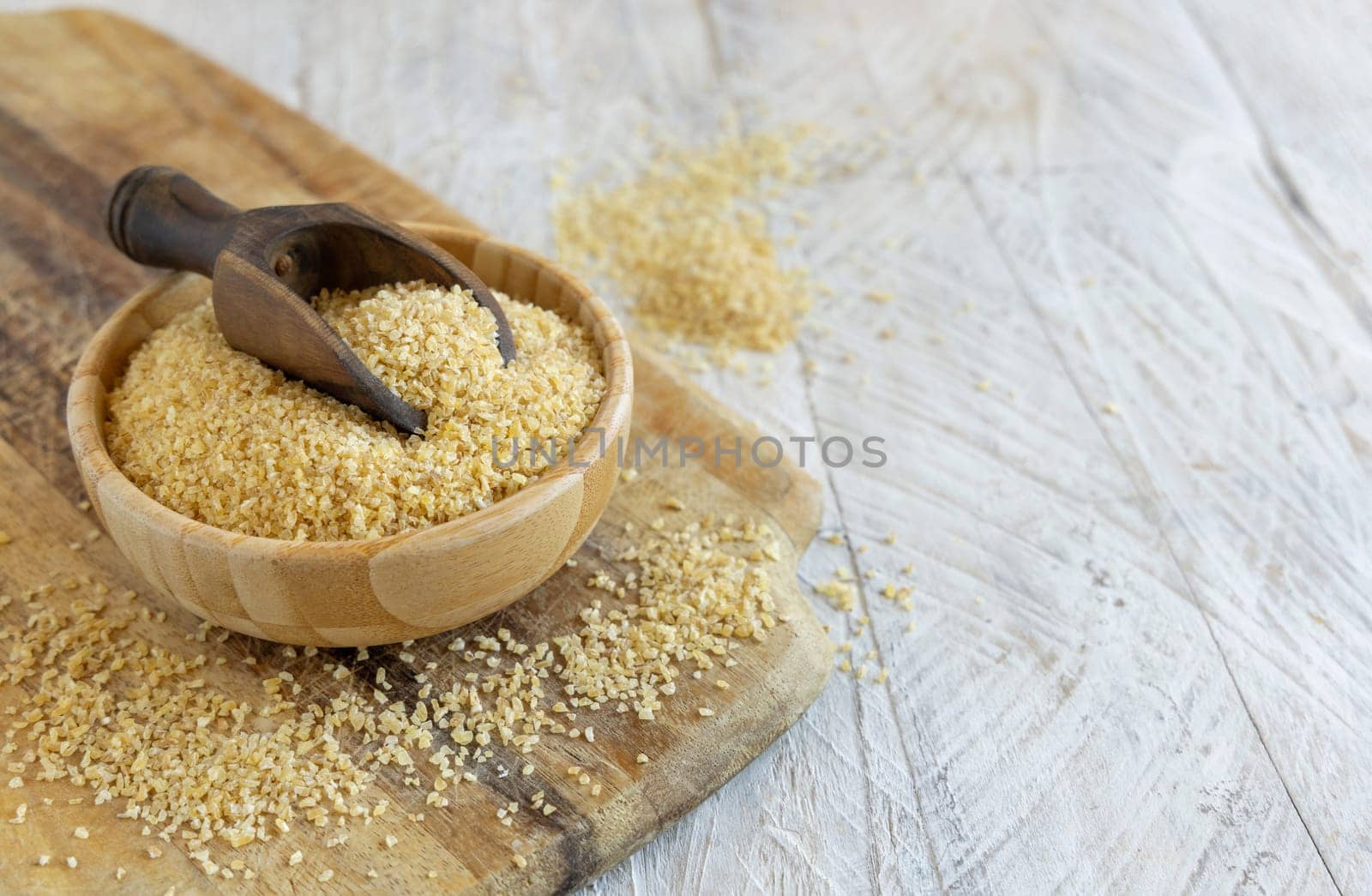 Raw Dry bulgur wheat grain in a wooden bowl with a scoop close up, copy space. Vegetarian and Vegan, Mediterranean and Middle Eastern cuisine. Healthy lifestyle