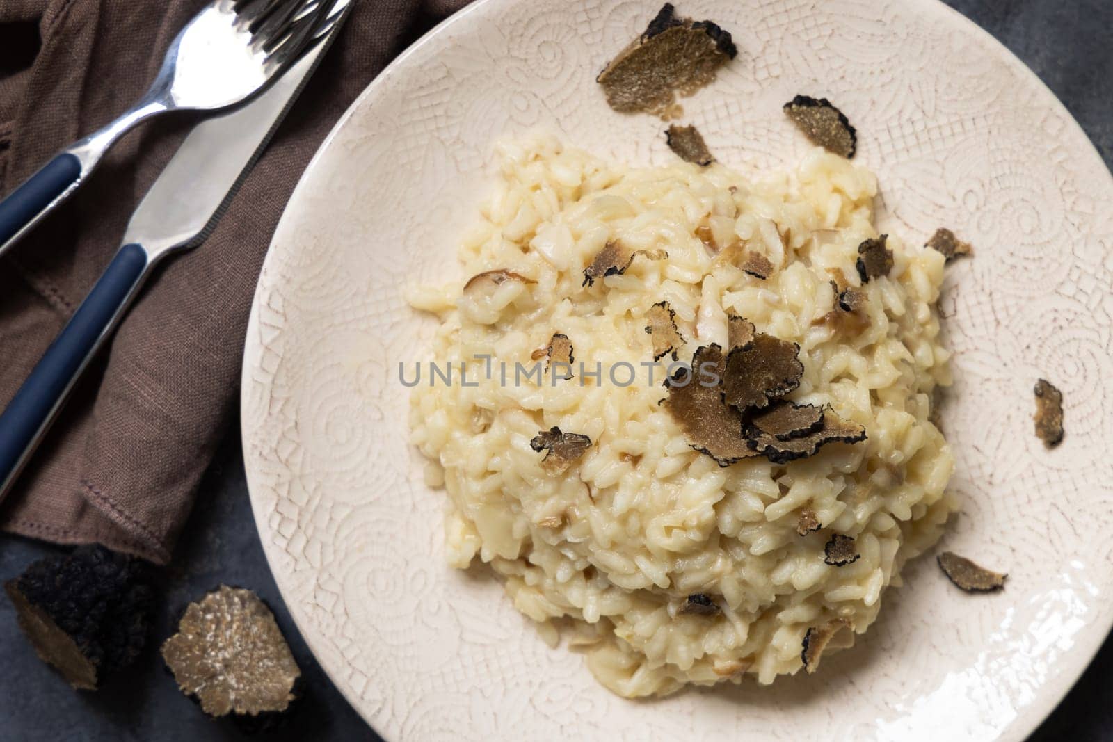 Risotto with wild porcini mushrooms and black truffles from Italy served in a plate top view on white table, copy space. Eating Italian gourmet cousine