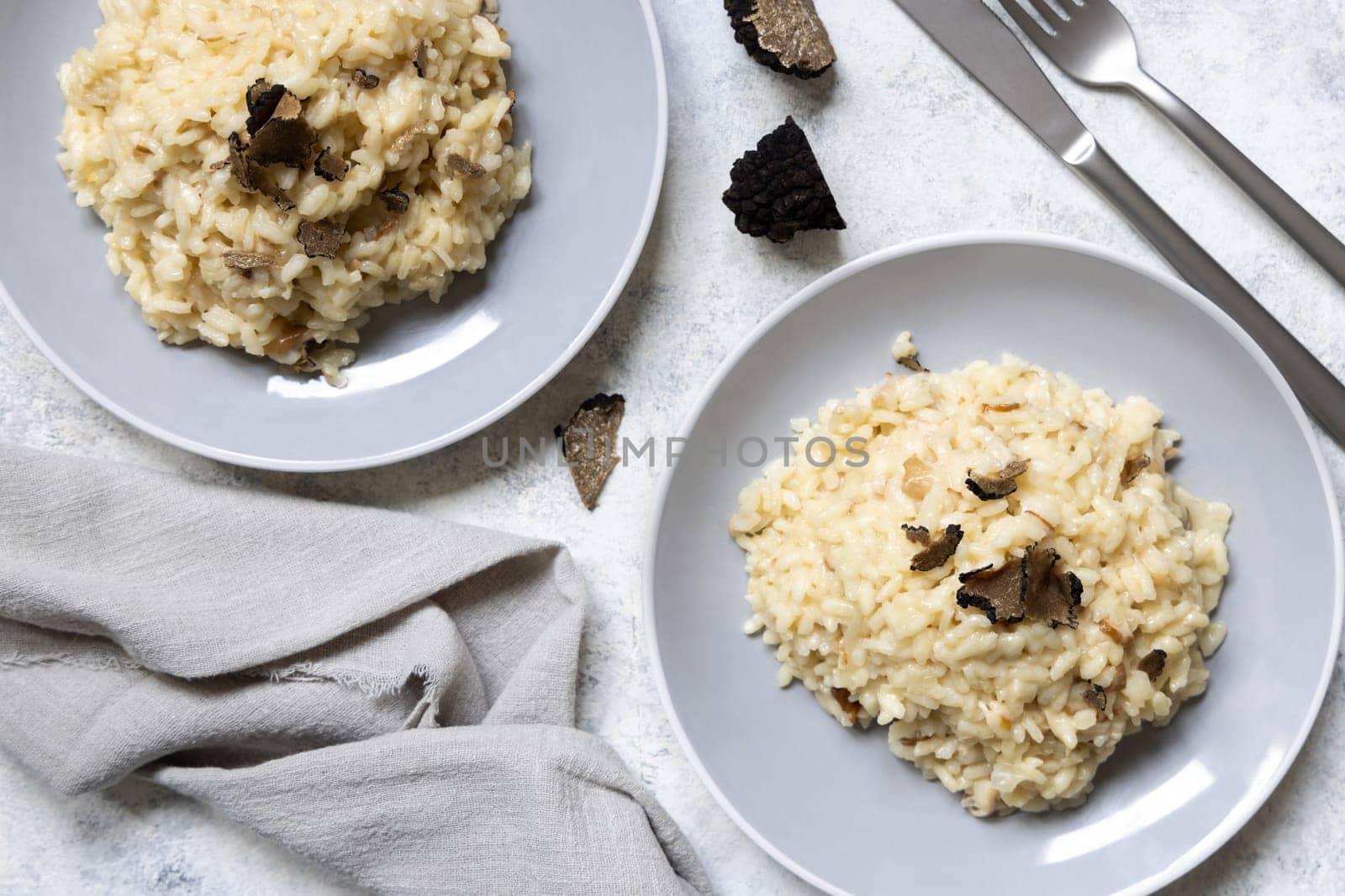 Risotto with wild porcini mushrooms and black truffles from Italy served in a plate top view on white table, copy space. Eating Italian gourmet cousine
