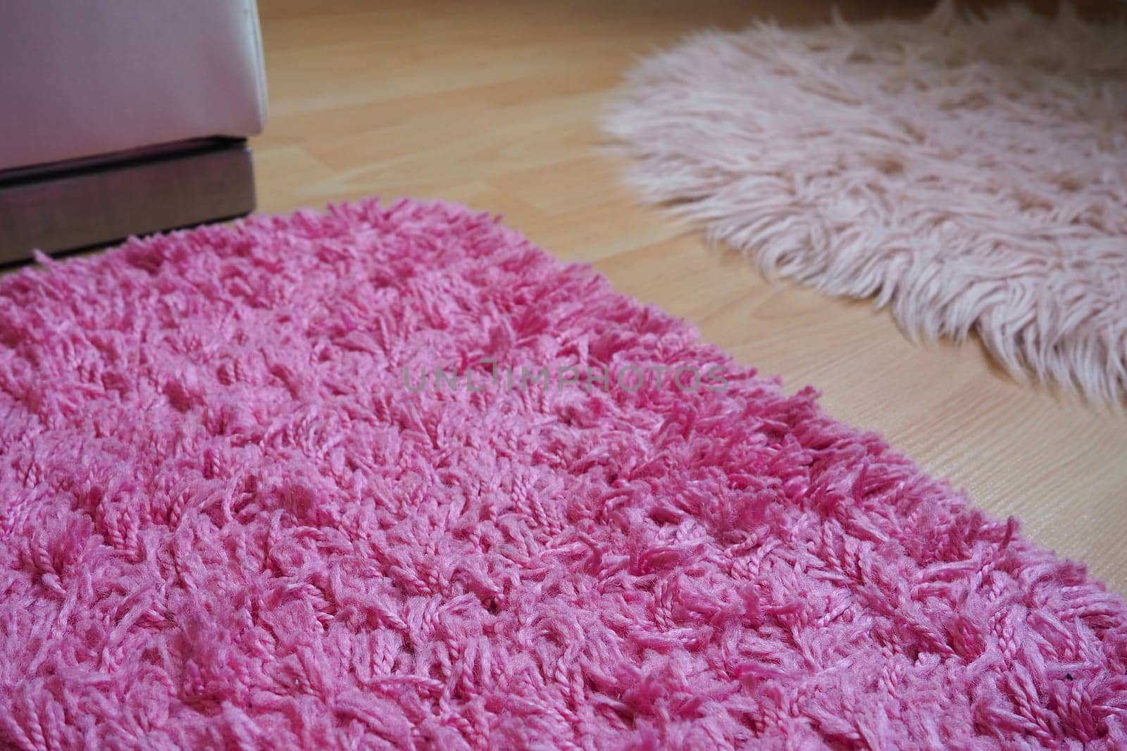 Long pile rug in pink on a beige laminate floor. Feminine interior for a room or bedroom of a girl or woman. Interior design in pink tones. Flooring is laminate. The role of dust mites in allergies