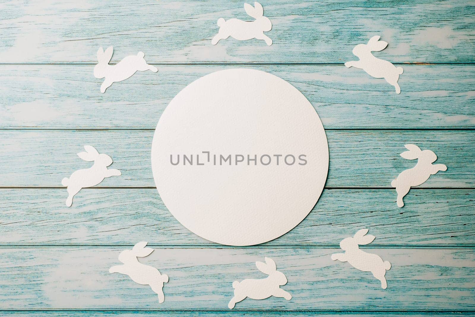 Easter Day Concept. Top view holiday banner background web design white circle paper circle space for text and bunny rabbit on blue wood background with copy space, celebration greeting card, overhead