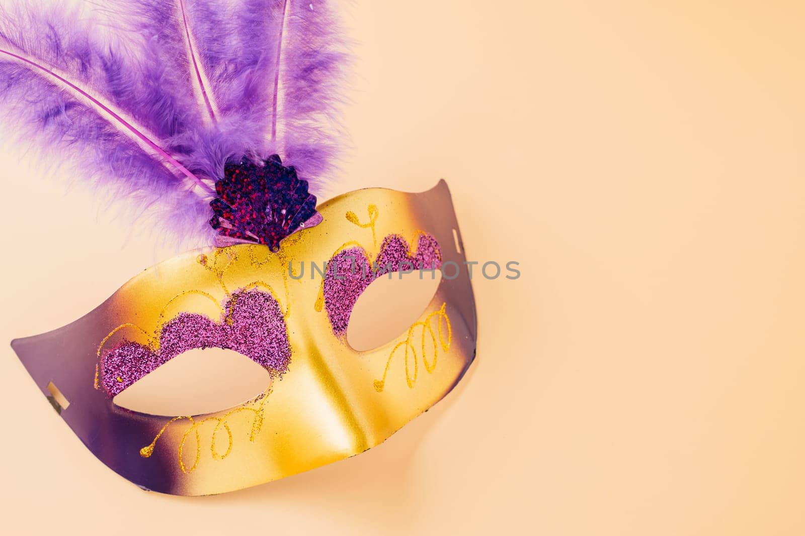 Happy Purim carnival decoration. Top view venetian ball mask with purple feather on pastel background, Jewish Purim and Mardi Gras in Hebrew, holiday background banner design, Masquerade party