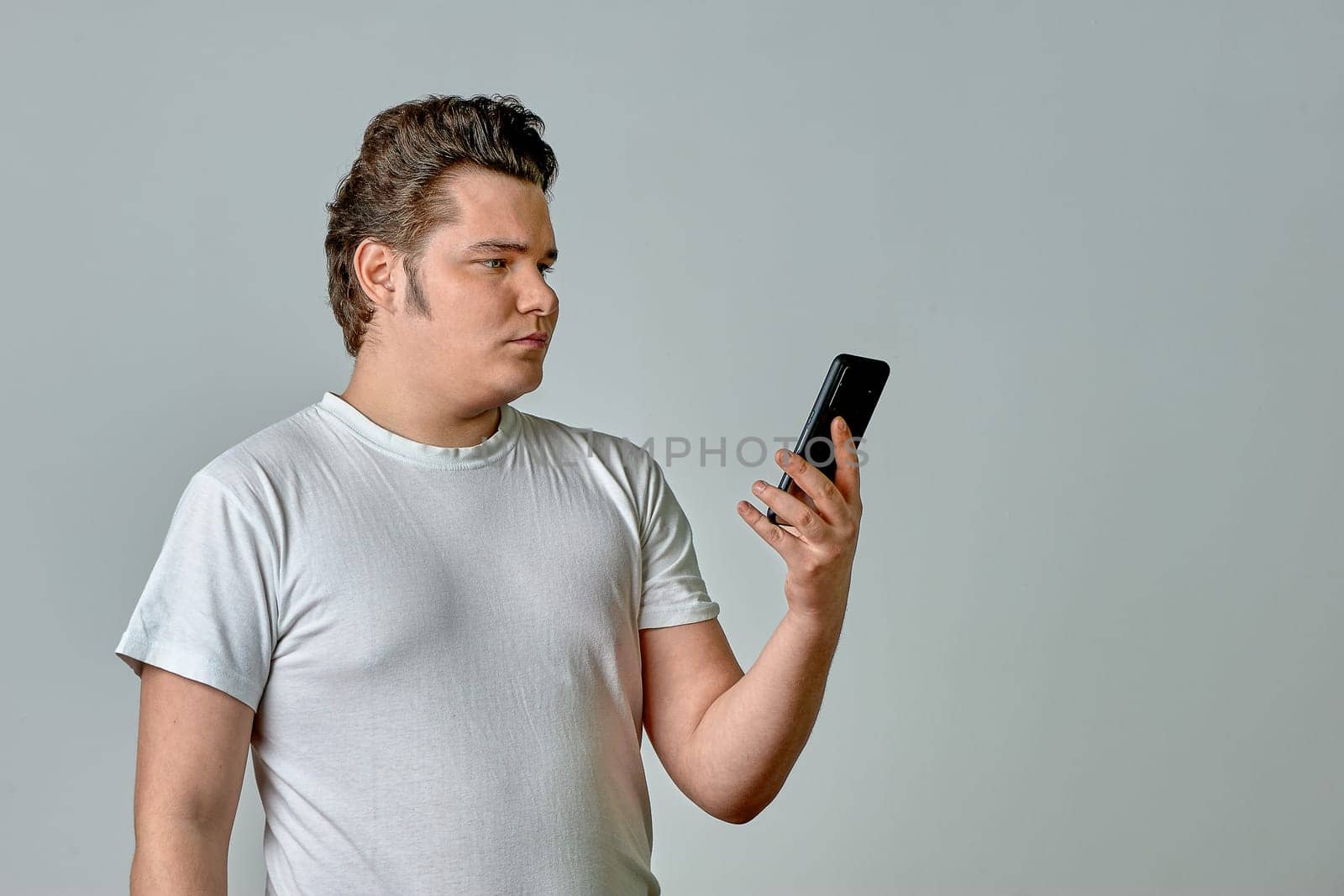 a man on a light background looks at the phone. High quality photo