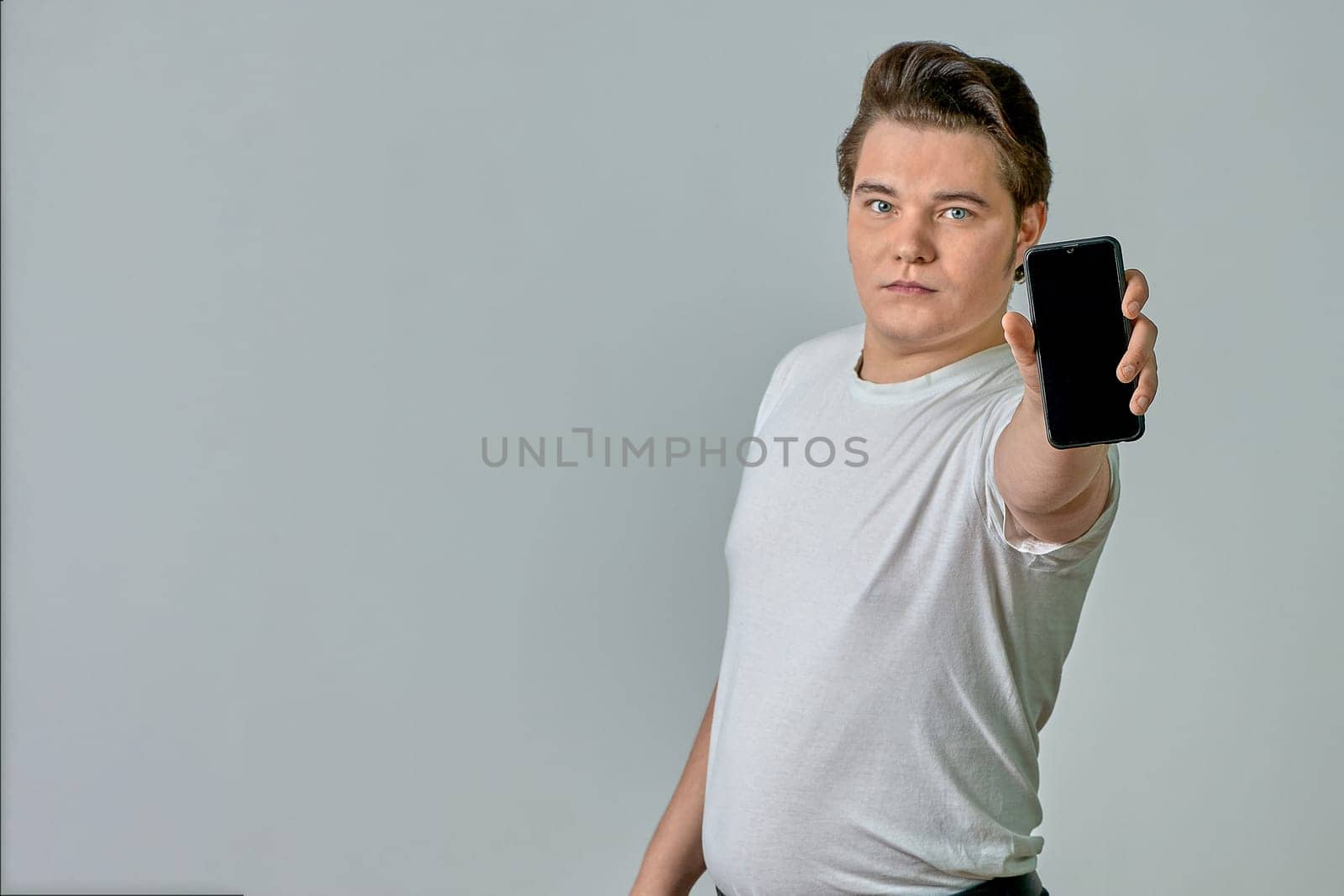 A man at arm's length shows a phone screen on a gray background. High quality photo
