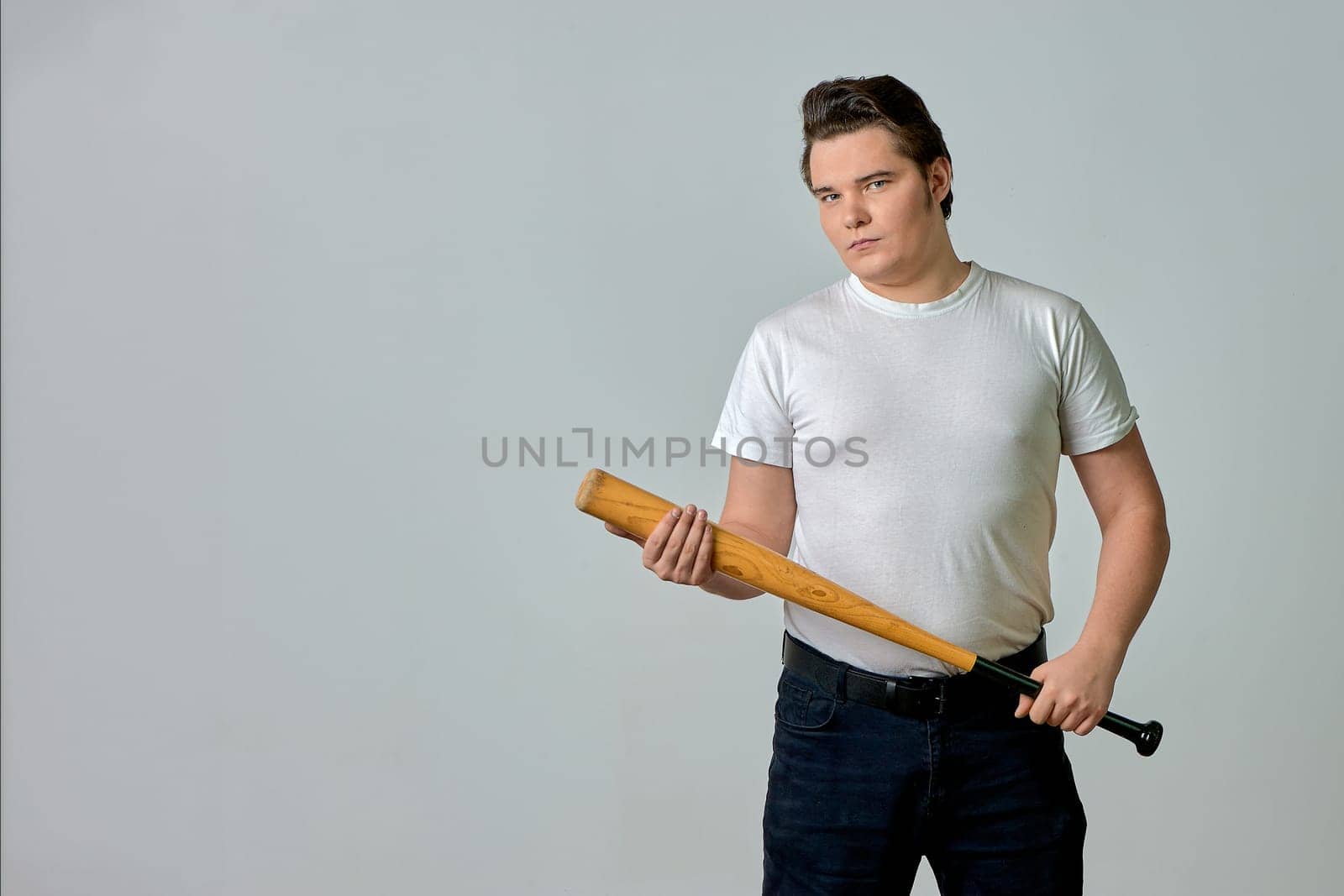 a man on a gray background holds a bat in his hands. High quality photo