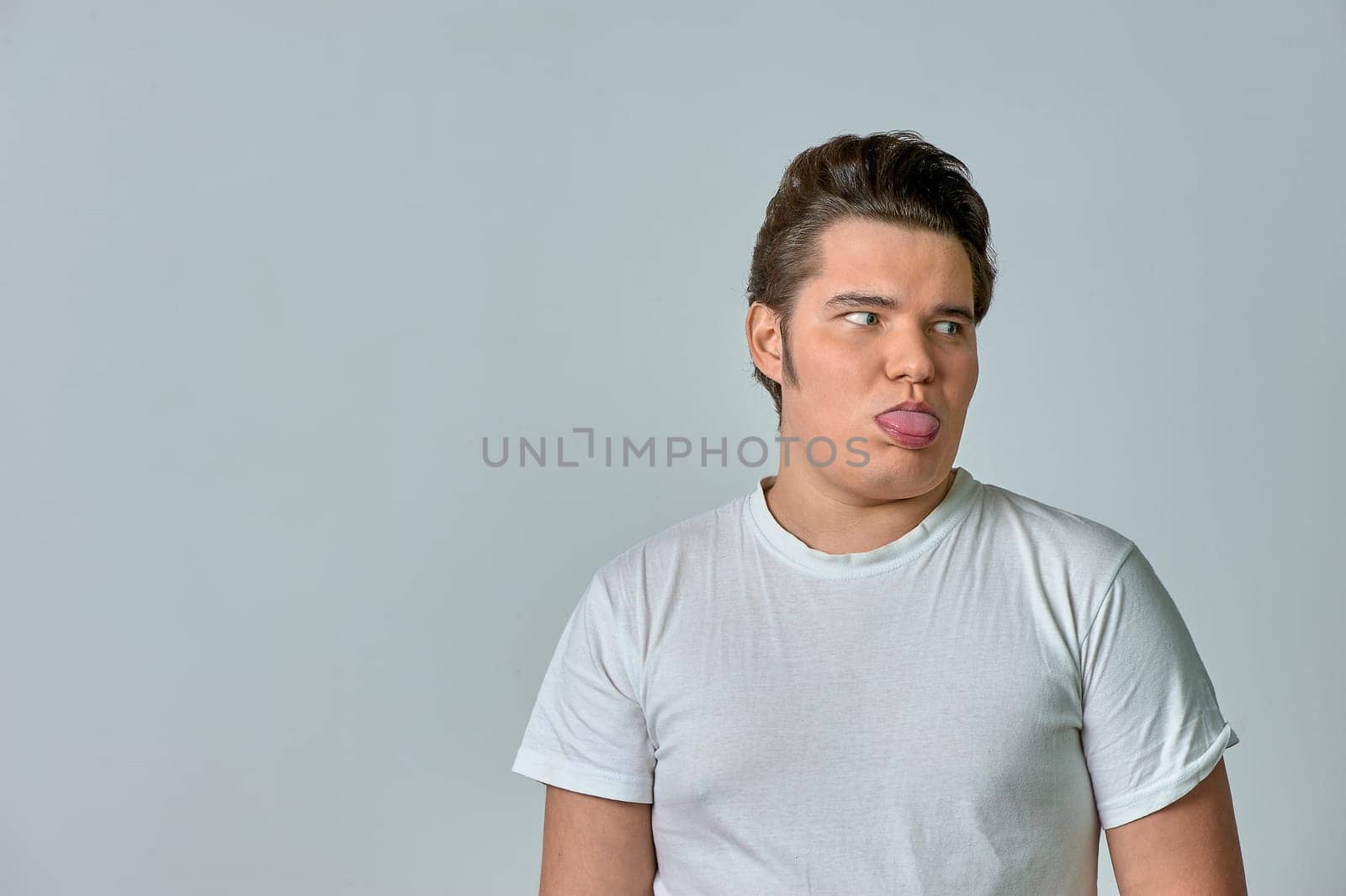 a man on a gray background shows his tongue. High quality photo