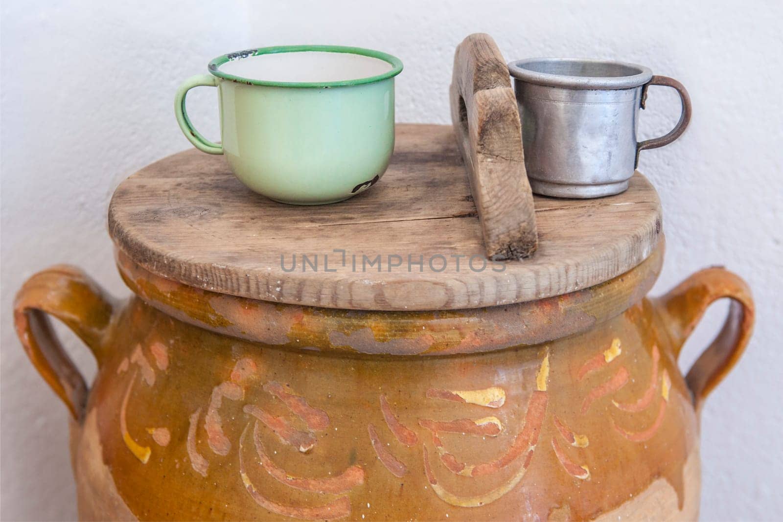 Large earthenware jar with lid and cups for drinking water. Old Cottage kitchen concept