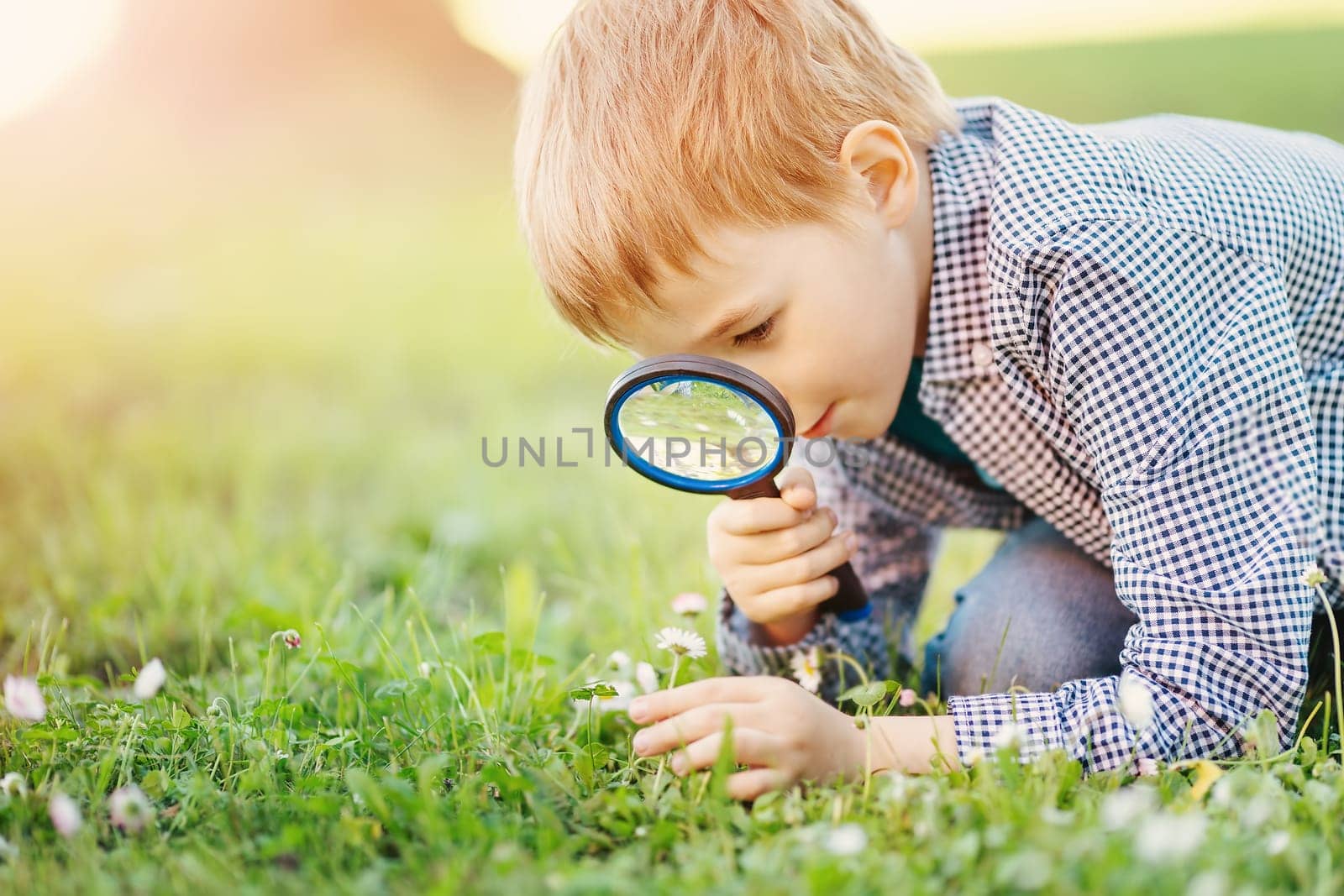 Boy with magnifying glass exploring the nature. Concept of the learning ecology and vacation.