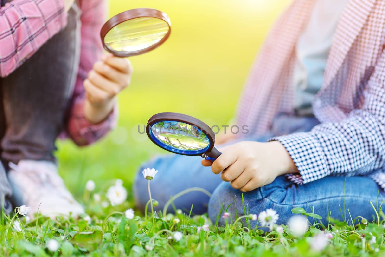 Children exploring fresh nature by using magnifying glasses. Concept of the family, vacation and recreation.