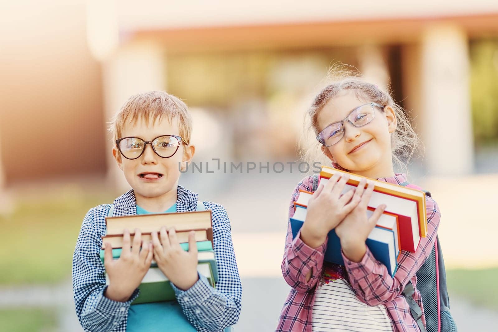 Girl and boy in glasses standing with books in their hands. Concept of back to school and studying.