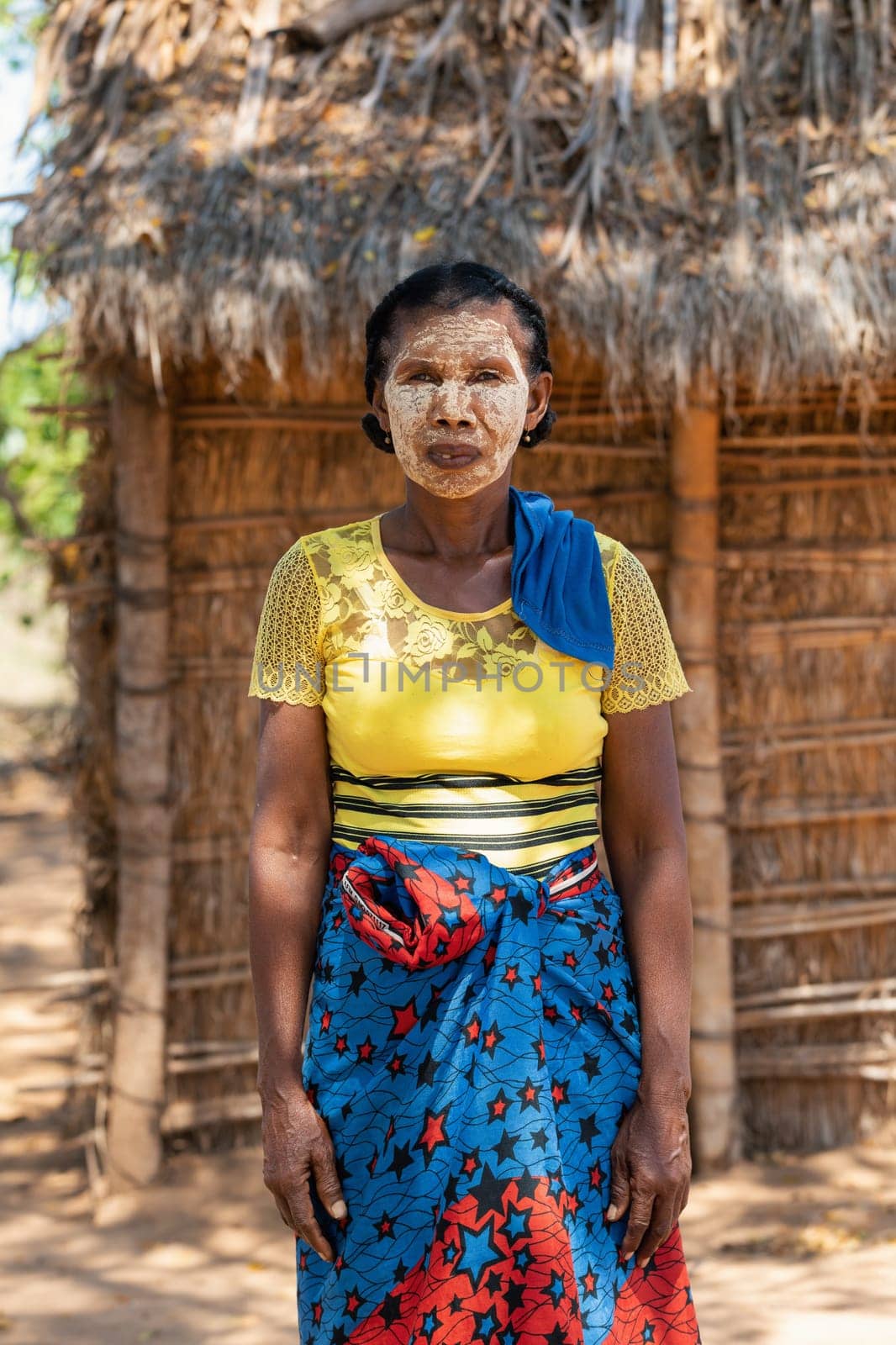 Belo Sur Tsiribihina, Madagascar - November 4. 2022: Malagasy woman in front of her hut with a traditionally painted face. Malagasy women paint their faces to protect their faces from the sun.