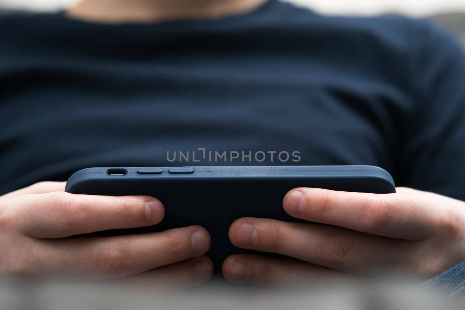 Unrecognizable close up blurred boy hands with smartphone in cover in horizontal orientation. Watching movies and surfing internet online, smart technology and application service. Streaming service