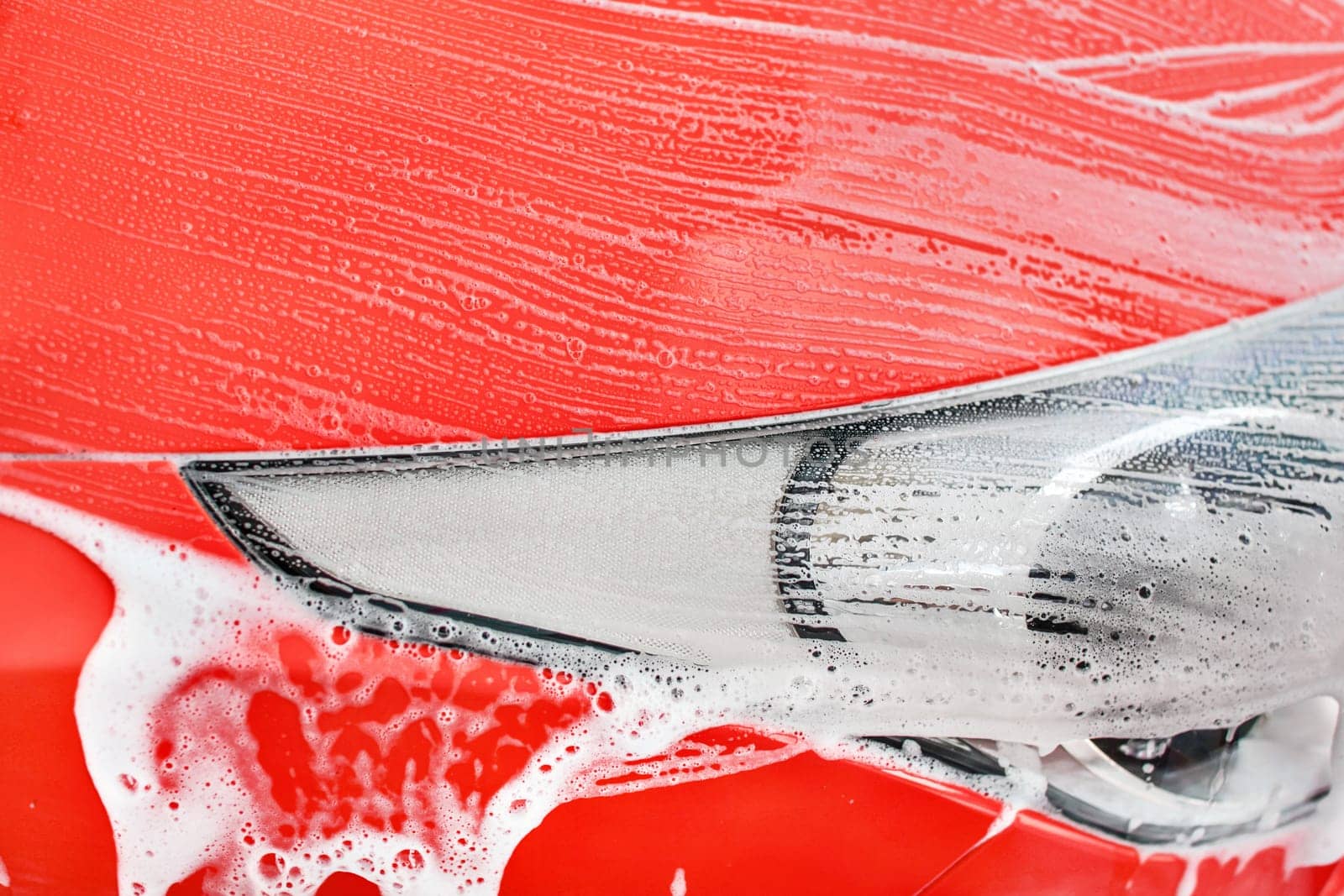 Detail on red car front light washed in carwash. (Color can be changed easily with hue/saturation tool)