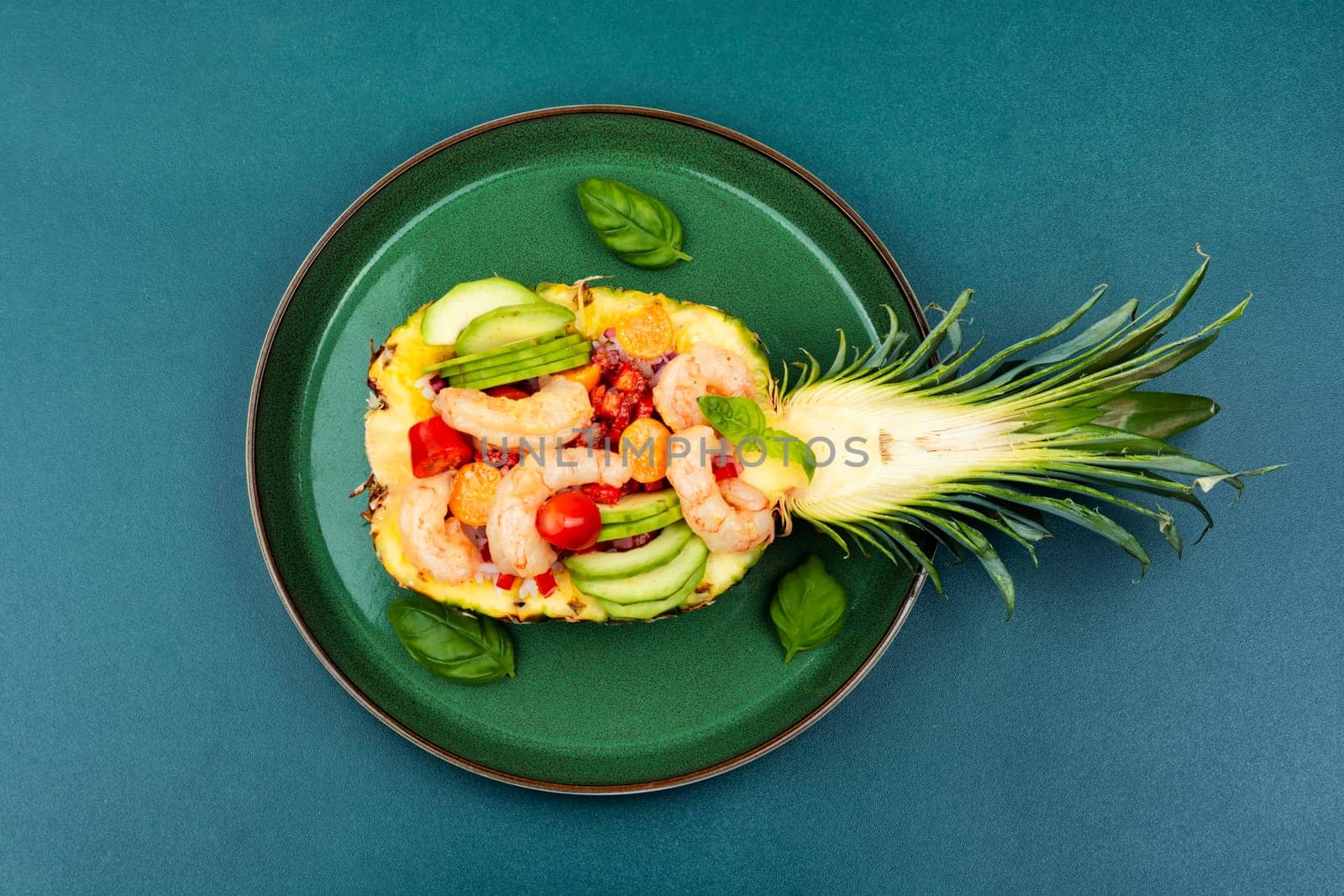 Half a pineapple with vegetables, rice and seafood on a white plate. Salad