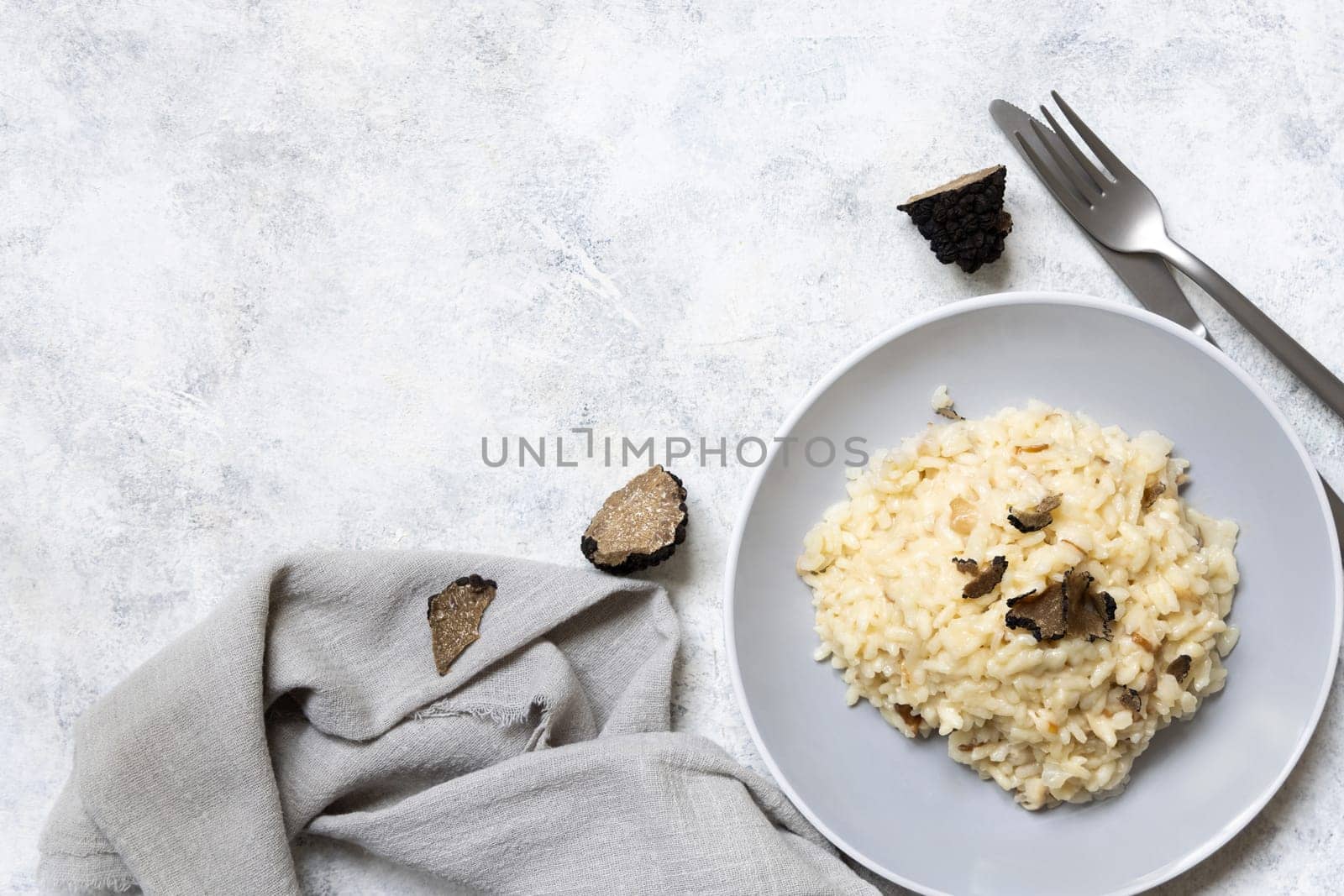 Risotto with wild porcini mushrooms and black truffles from Italy served in a plate top view on white table, copy space. Eating Italian gourmet cousine