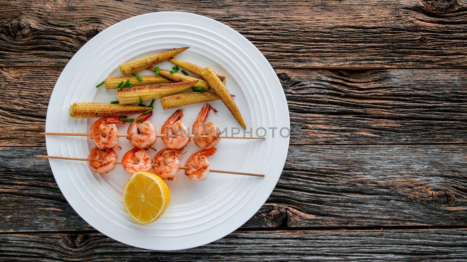 Close up from shrimps with baby corn on white plate  from above