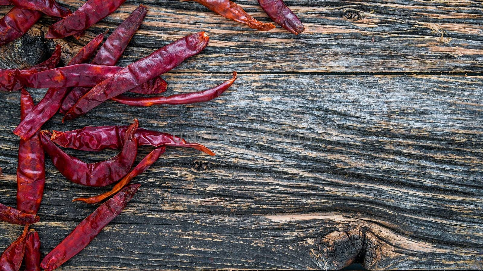 Dry sicy red pepper on rustic wooden background from above with copy space on bottom