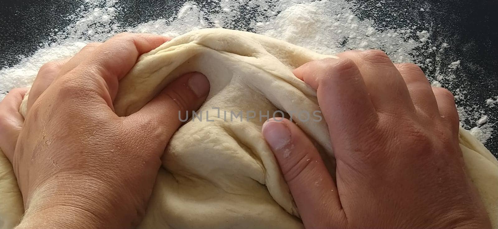 Hands knead the dough. The woman kneaded dough for baking or dumplings. Preparation of flour, water and egg mass for thermal processing. Chef hands.